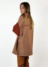 Chaqueta marrón con diseño de espiga, cuello camisero, cierre con botones y un bolsillo de parche en el pecho. Las mangas son largas y de punto color ladrillo.