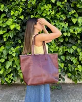 Bolso grande de cuero marrón, tipo shopper, con costuras artesanales decorativas en contraste a lo largo del borde superior y las asas de hombro.