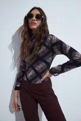 Body de mangas largas con cuello alto, confeccionado en tejido de tul semitransparente con estampado animal print en tonos grises y negros.