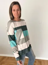 Remera de manga larga en tejido liviano con diseño de rayas anchas en tonos fucsia, gris y crudo. Corte recto y cómodo con bolsillo delantero.