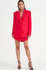 Blazer fucsia con solapa de muesca, hombreras marcadas y un único botón frontal. Incluye dos bolsillos de parche en la parte delantera.