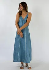 Pollera midi celeste de lino con breteles finos y corte evasé. Presenta detalles de líneas verticales blancas en los laterales.