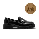 Mocasín de cuero charolado color negro, con suela track de goma y detalle de aplique metálico plateado en el empeine.