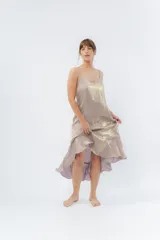 Vestido midi color lila metálico de breteles finos regulables, escote en V y ruedo asimétrico con leve vuelo.