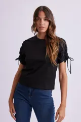 Remera negra de manga corta con cuello redondo y fruncidos ajustables mediante cordones en las mangas.