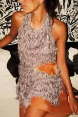 Vestido minifalda con cuello halter, confeccionado en tela de flecos y lentejuelas, con espalda al aire.