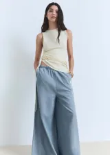 Pantalon palazzo de tiro medio confeccionado en tejido mezcla de algodón y lyocell. Presenta cintura con elástico, diseño largo y dos bolsillos laterales.