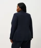 Blazer de corte sastre confeccionado en crepé, con diseño alargado y cierre frontal de doble abotonado con botones forrados. Presenta solapas clásicas y estructura recta.