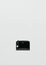 Billetera pequeña de diseño rectangular en acabado charol negro. Cuenta con cierre perimetral con tirador decorativo y detalle de logo metálico en el frente.