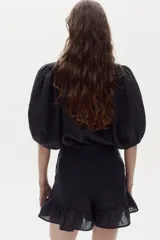 Short negro de lino 100% natural, de tiro medio-alto, con elástico interno en la cintura, bolsillos laterales y volados decorativos en el ruedo.