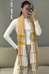 Bufanda rectangular de tejido suave con diseño de cuadros escoceses en tonos mostaza, blanco y gris, terminada con flecos en los extremos.