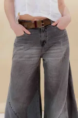 Pantalón de jean color beige, de tiro medio, corte amplio y ruedo acampanado.