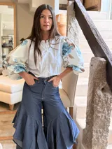 Camisa de popelina con cuerpo central blanco y mangas abullonadas con estampado floral en tonos celestes y marrones, cuello redondo y cierre frontal de botones.