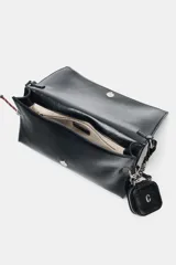 Bolso de hombro tipo baguette en color negro, con acabado brillante y estructura rectangular. Cuenta con una correa combinada de cadena metálica plateada y cuero sintético, y un pequeño monedero extraíble unido a un lateral. Presenta detalles de cordones decorativos en el otro lateral y cierre mediante solapa con imán.