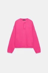 Sudadera fucsia con efecto lavado, confeccionada en mezcla de algodón. Cuenta con cuello redondo con una pequeña abertura frontal con botones, manga larga caída y puños y dobladillo en rib.