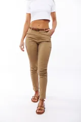 Pantalón de vestir color beige, de corte recto, con bolsillos laterales y traseros. Se ajusta a la cintura con cinturón de cuero marrón.