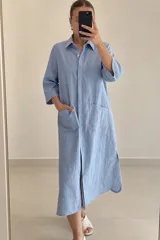 Vestido midi estilo camisero celeste, de manga 3/4, con cuello camisero, bolsillos frontales aplicados y tajo en la parte inferior.