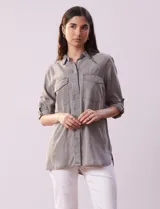 Camisa celeste de tencel con cuello con solapa, abertura central con botones ocultos, bolsillos delanteros y mangas largas regulables con presilla y botón.