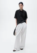 Camisa negra de manga corta, confeccionada en tejido de lino y algodón, con cuello camisero, diseño recto y cierre frontal de botones.
