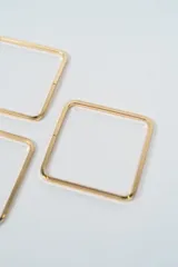 Set de tres brazaletes rígidos de forma cuadrada, fabricados en metal plateado con acabado brillante.