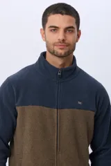 Campera polar bicolor de diseño texturado suave al tacto, con cuello alto, cierre frontal completo y bolsillos laterales. Presenta una combinación de color azul marino en la parte superior y marrón en la inferior, con un pequeño logo bordado en el pecho.