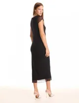 Vestido midi negro con cuello redondo, mangas cortas de microtul transparente y ruedo con acabado roulette. Presenta un forro interno opaco y una capa exterior de microtul, con un tajo lateral profundo.