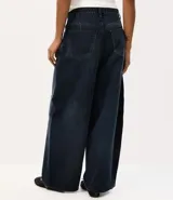 Pantalón barrel de jean color azul oscuro con lavado desgastado, de cintura alta, corte amplio en las piernas y botamanga afinada. Cuenta con cierre frontal y bolsillos funcionales.