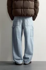 Pantalón jeans de corte relaxed fit, color celeste con efecto lavado, de estilo carpintero con bolsillos laterales y presillas de herramientas.