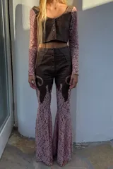 Pantalón de tiro alto y corte oxford confeccionado en cuero y encaje color negro. Presenta paneles de cuero en la parte superior con botones frontales y piernas de encaje transparente con diseño acampanado.