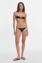 Top de bikini ajustable de color blanco crema con estampado de lunares negros, detalles de vivos en contratono camel y escote en V con ribete negro.