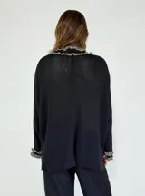 Saco color crudo de tejido de punto con detalle de volados en el frente y en los puños.