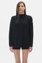 Buzo tejido negro con cuello alto tipo polera, corte oversized y aberturas laterales.