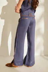 Pantalón azul marino de corte wide leg con detalles en tono marrón tostado en la cintura, bolsillos y bordes laterales, cuenta con trabillas para cinturón y cierre frontal.