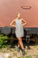 Vestido corto de color beige con cuello halter, diseño sin mangas y cierre frontal con botones dorados.