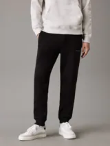 Pantalón de chándal negro de felpa de mezcla de algodón reciclado, con cintura elástica con cordón, puños de canalé, bolsillos con ranura y bolsillo trasero. Presenta un monograma bordado de Calvin Klein en la pierna.