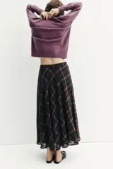 Falda midi de tiro alto con diseño acampanado y estampado de cuadros en tonos negro y marrón. Cuenta con cierre lateral oculto.