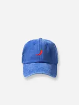 Gorra tipo baseball de color azul con efecto lavado, que presenta un bordado pequeño de un ají rojo en la parte frontal central.