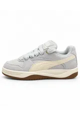 Championes Puma modelo Park Luna de color marrón topo, confeccionados en gamuza con detalles en cuero sintético blanco crudo, cordonera gruesa y suela de goma marrón.