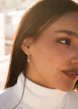 Par de aros dorados tipo argolla con incrustaciones de circonitas y dije colgante de rayo con circonitas.