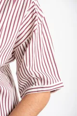 Camisa de corte oversize con estampado de rayas verticales, cuello clásico y mangas cortas. Presenta cierre frontal con botones y un diseño fluido y ligero.