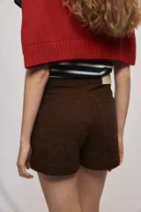 Short de tiro medio y calce ajustado, color blanco, con dobladillos en las piernas y cierre frontal con botón.