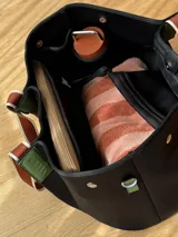 Bolso tipo tote de neopreno en color verde oliva, con correas de hombro en color rojo y detalles en blanco. Cuenta con broches imantados laterales para ajustar su forma y un bolsillo interno de red.