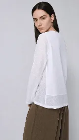 Remera de manga larga confeccionada en una combinación de lino y algodón. Presenta escote en V, diseño con cortes frontales y detalle de logo bordado. Posee un calce cómodo con aberturas laterales en el ruedo.