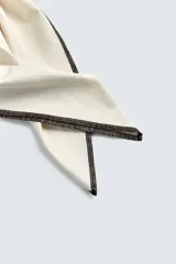 Bandana cuadrada de algodón color crema con bordes cosidos en contraste negro.