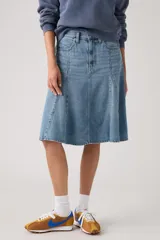Falda midi de denim en tono azul claro, con diseño acampanado y paneles verticales tipo godet.