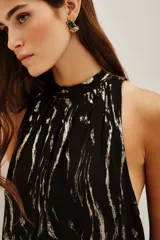 Top sin mangas de cuello alto con frunces, confeccionado en tela negra con estampado de cebra en hilo metalizado. Posee forro interior.