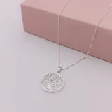 Conjunto de collar y caravanas de plata con dije de nácar con diseño de árbol de la vida.