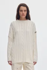 Buzo negro de tejido de ochos, con cuello redondo y diseño oversized de corte largo y amplio con tajos laterales.