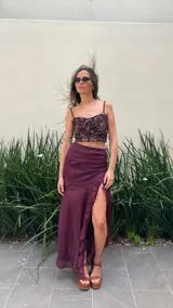 Pollera larga de gasa color bordó, con diseño de tiro alto, base fruncida y tajo lateral profundo decorado con volados verticales.