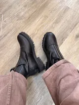 Botas de cuero color marrón con diseño estilo brogue, cierre lateral y suela track negra de goma resistente.